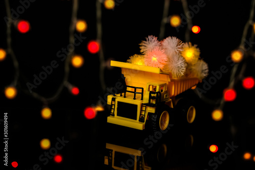 Christmas card. Children s car carries bright festive garlands. Dark background  yellow color. Happy Chrismas Concept