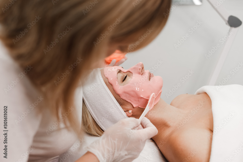 Cosmetologist applies a mask on the face of the client Cosmetologist applies a mask on the face of the client