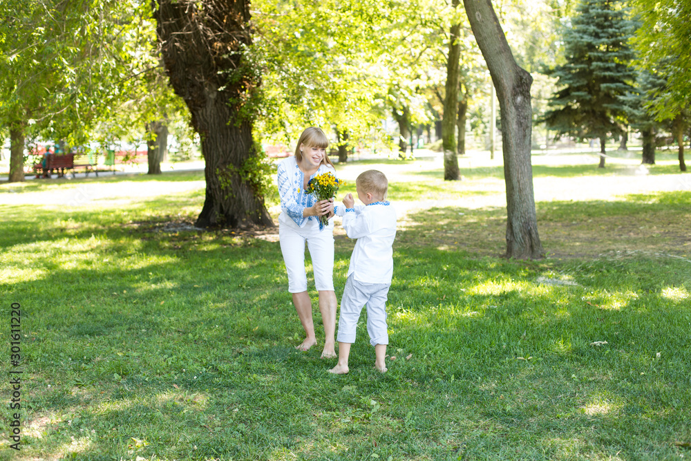 mother and son in embroidered shirts. national clothes of Ukraine. a boy gives flowers to his mother mother and son in embroidered shirts. national clothes of Ukraine. a boy gives flowers to his mother