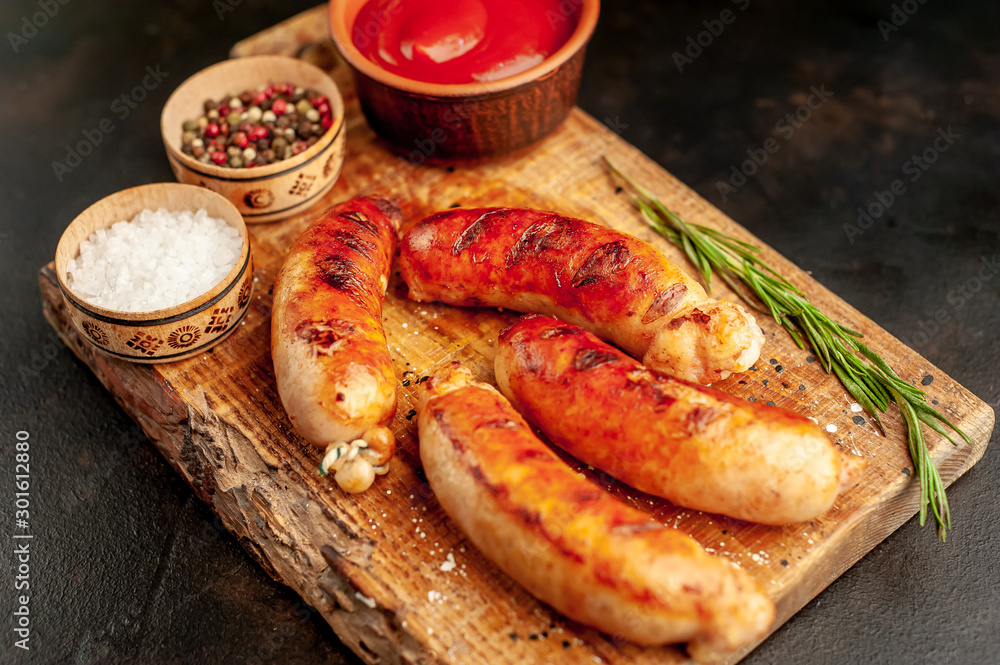 Grilled sausages with spices, ketchup and rosemary on a stone table, ready to eat Grilled sausages with spices, ketchup and rosemary on a stone table, ready to eat