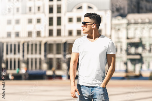 Outdoors Leisure. Stylish guy in sunglasses standing on the street hand in pocket looking aside pensive photo
