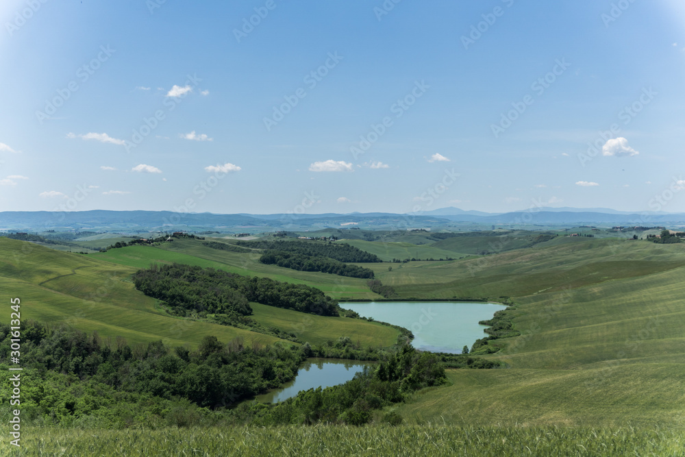 landscape with, ponds, green fields and blue sky in Tuscany, Italy