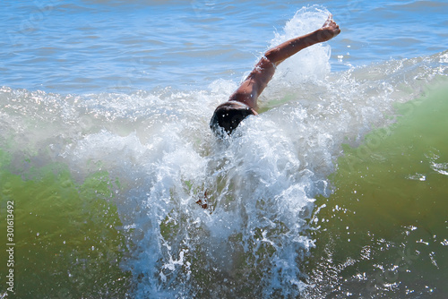 A man swims in the sea during high waves. Rough turbulent sea. Man is struggling with the elements.