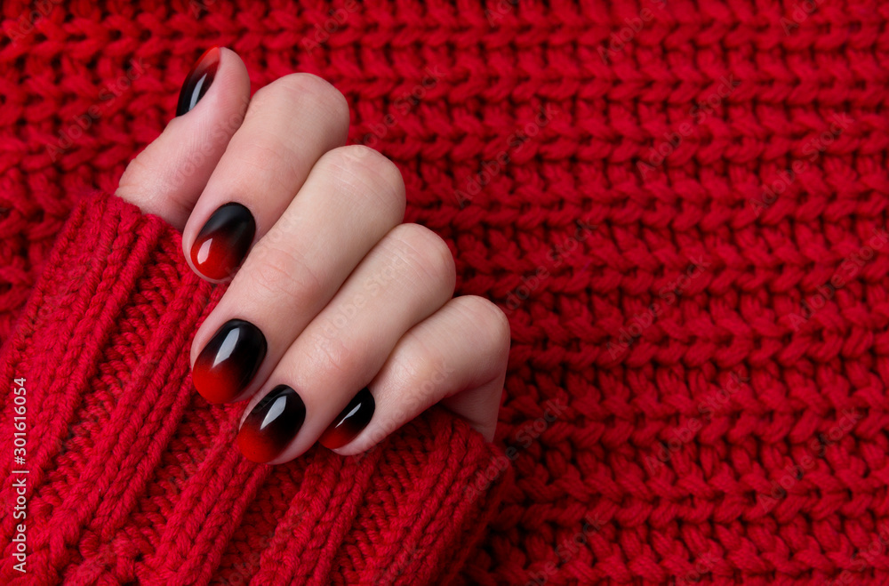 Female hand with red black ombre gradient nails in sweater Stock Photo |  Adobe Stock