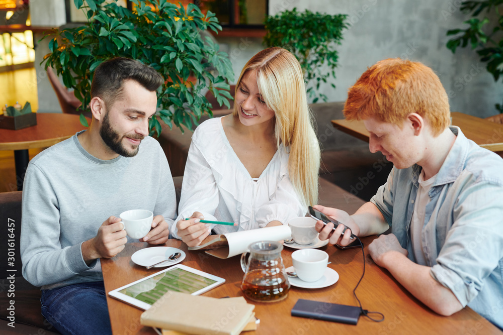 Fototapeta premium Pretty girl showing her boyfriend notes in notepad while preparing for seminar