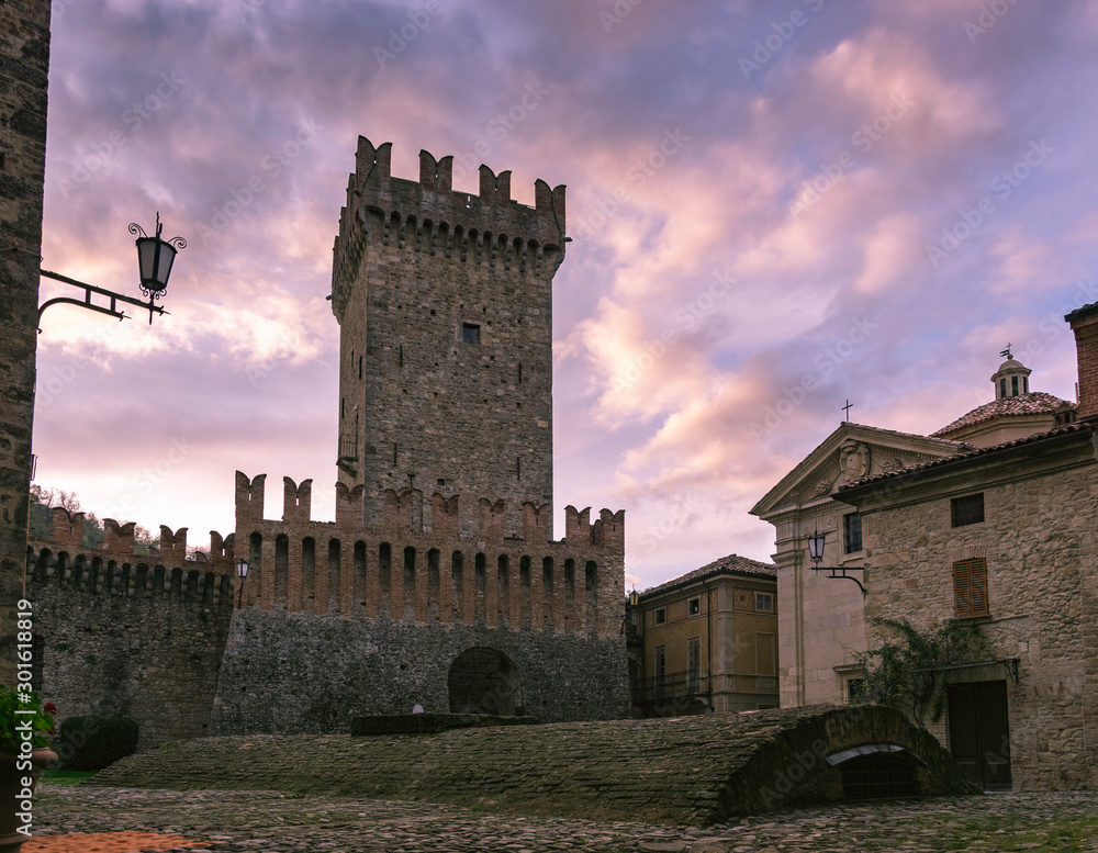 View of the square and castle in the medieval village of Vigoleno in Italy during sunset, with romantic sky