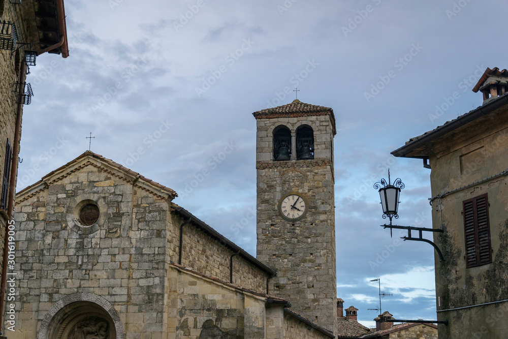 Facade of an ancient church with bell tower in a village in Italy