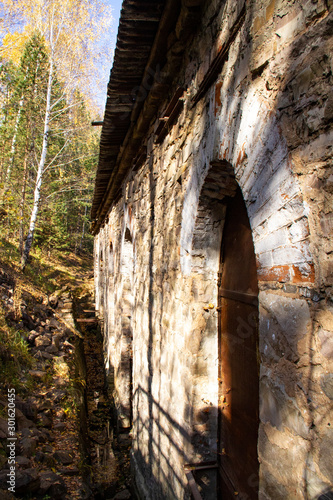 Old hydroelectric building on a mountain river made of vintage stone.