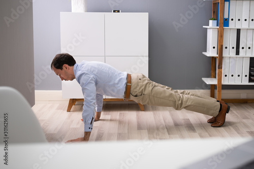 Businessman Doing Pushups At Work