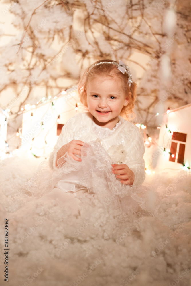 Fototapeta premium girl in Christmas decorations with artificial snow and small cardboard houses