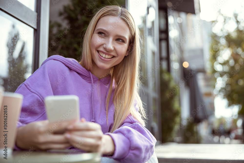 Joyful girl having fun while waiting for coffee
