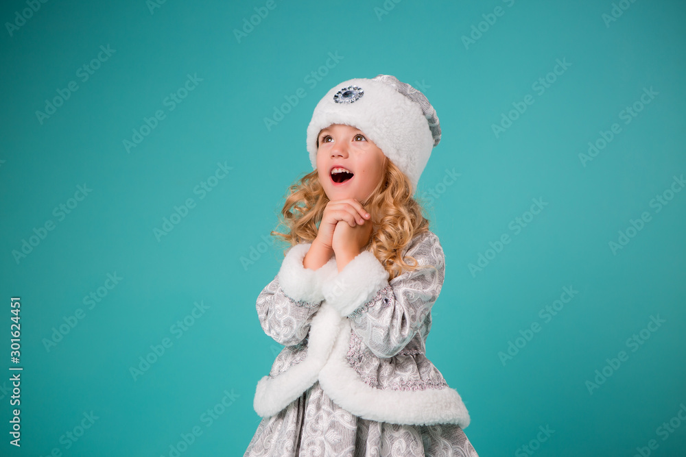 little blonde girl smiling in snow maiden costume isolate on blue background, baby catches snowflakes little blonde girl smiling in snow maiden costume isolate on blue background, baby catches snowflakes