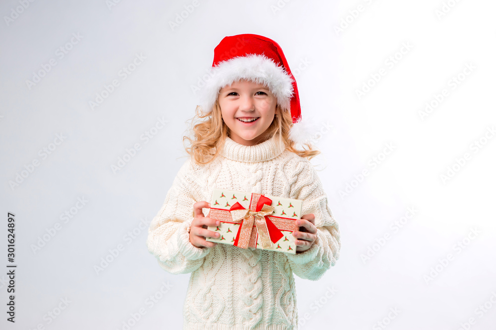 little blonde girl in Santa hat holding gift box, isolate on white background, space for text little blonde girl in Santa hat holding gift box, isolate on white background, space for text