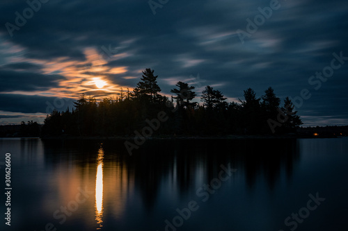 A night time silhouette of an island with the moon rising