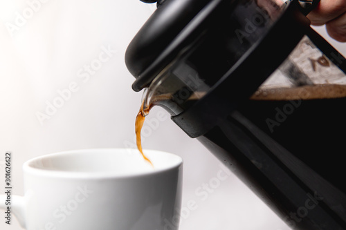 A french press pouring a cup of coffee