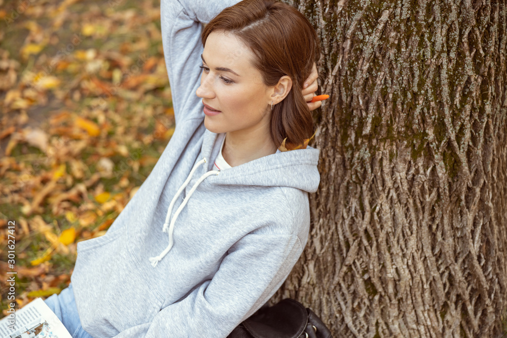 Obraz premium Portrait of pleased girl that leaning on tree
