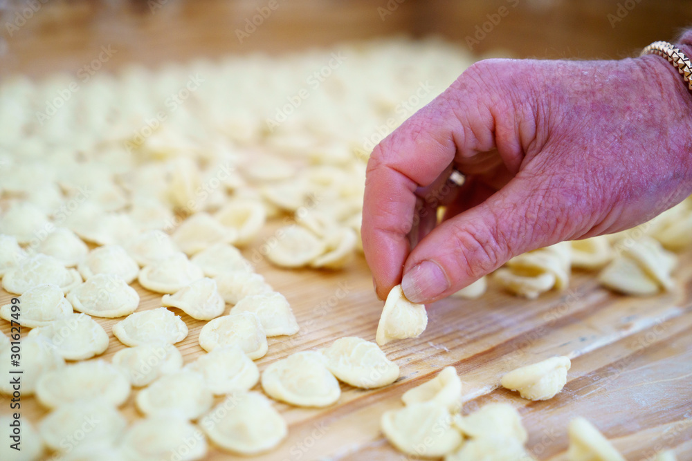 Hands making orecchiette pasta, typical of Apulia, a region of Southern Italy. Their name comes from their shape, which resembles a small ear. Hands making orecchiette pasta, typical of Apulia, a region of Southern Italy. Their name comes from their shape, which resembles a small ear.