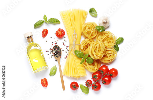 Flat lay composition of raw different pasta, fettuccine balls, cherry tomatoes, , spices, basil, olive oil, garlic isolated on a white background.