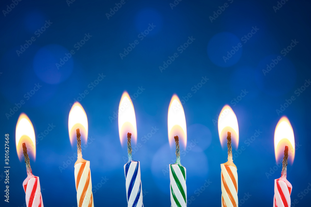Colorful and funny birthday candles are lit on a blue background