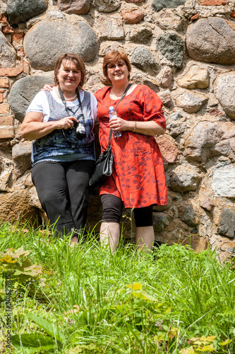 Two Mature plump female tourists inspect an ancient castle on the island. Trakai castle,