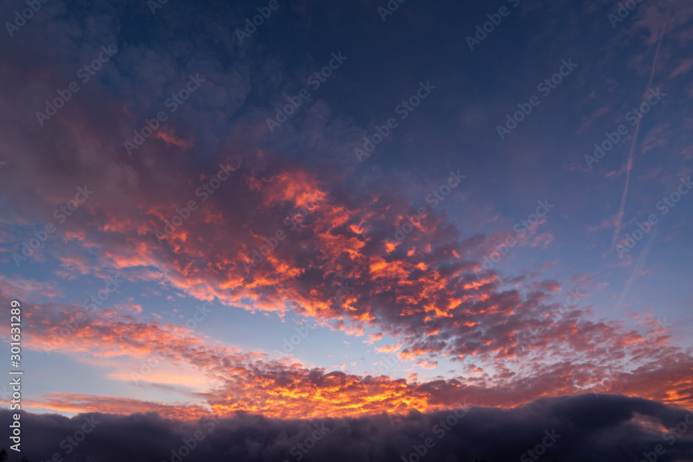 A dramatic sunset or sunrise sky with clouds. Orange and purple colors on a dramatic looking sky.