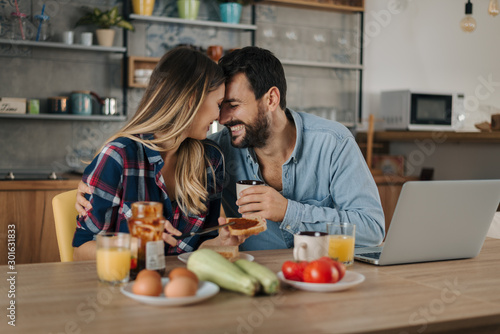 Young smiling couple flirting while having a breakfast at home
