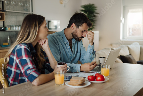 Young couple feeling stressed while have to pay their bills over Internet