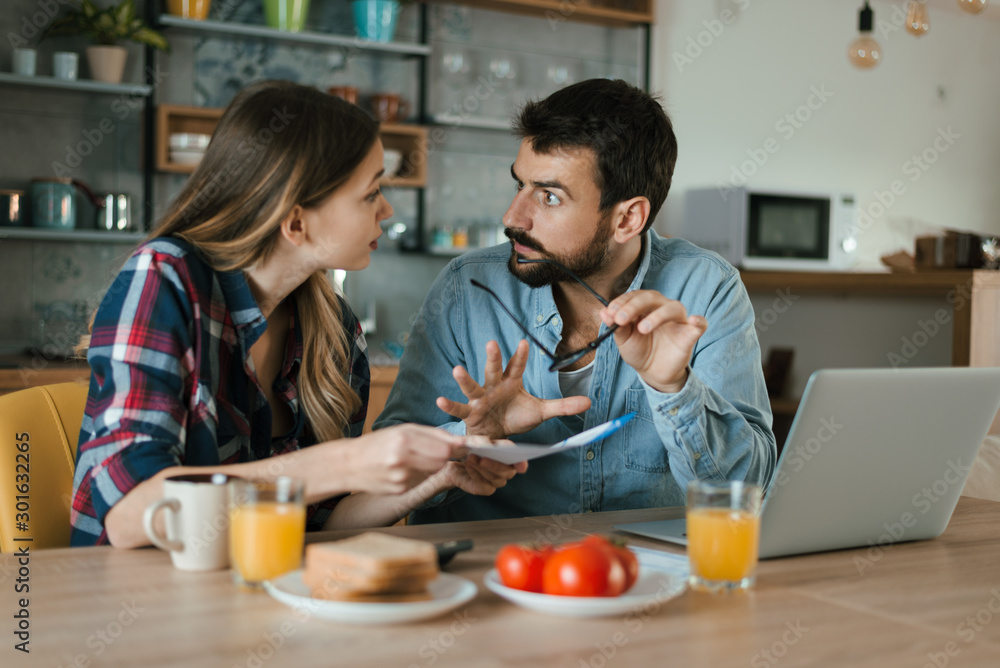 Young couple arguing while having problems with their home finances at dining table