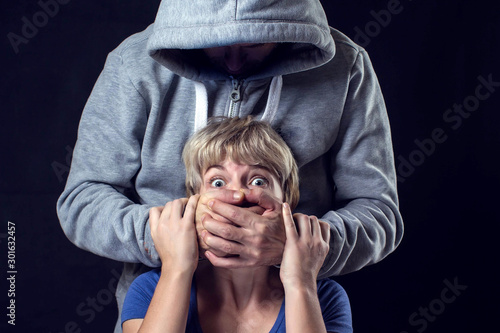 Man's hand covering a woman'smouth. Concept of violence or kidnapping.