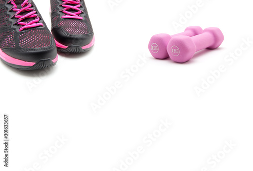 Sport shoes and two of pink dumbbells isolated on white background