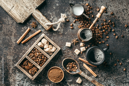 Coffee cup, sugar, milk and coffee beans on dark background.