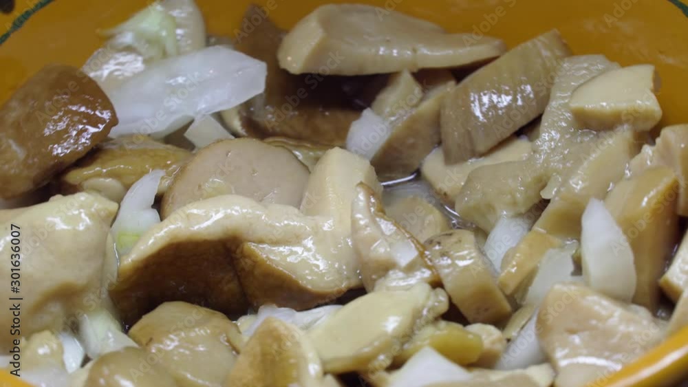 Pickled mushroom salad with green onions and butter rotates on a plate. Pickled mushroom salad with green onions and butter rotates on a plate.