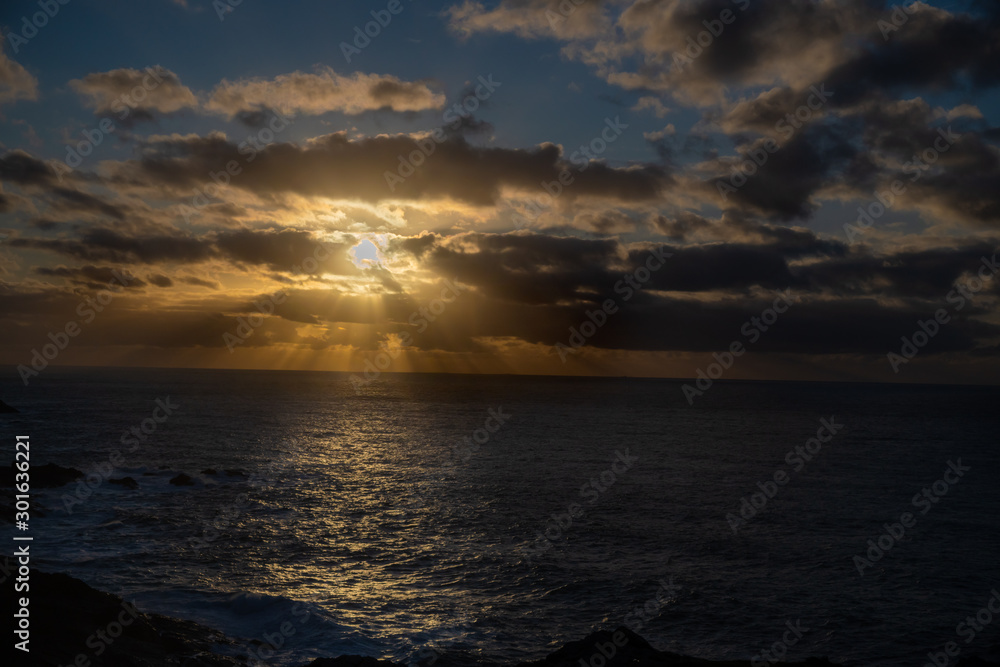 Sun rays behind cloud at sunset cloudscape seascape in Cornwall