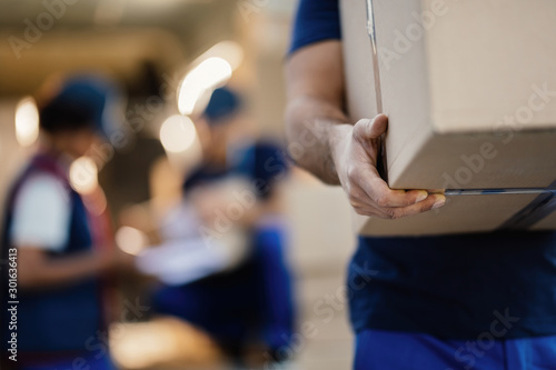 Close-up of unrecognizable delivery man with cardboard box.
