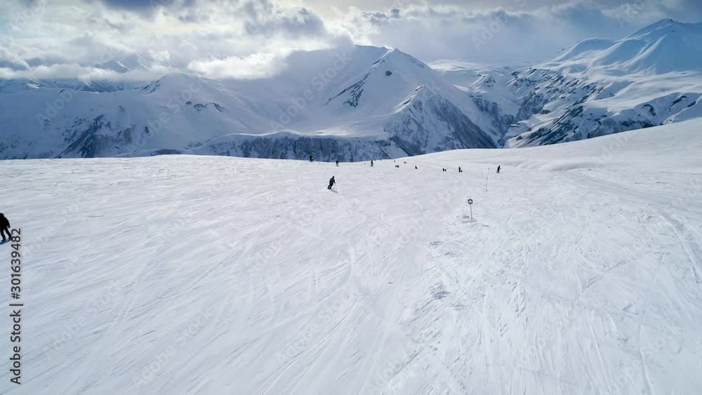 Skiers and snowboarders riding down the mountain slope. Aerial flight above mountain ski resort Gudauri, Georgia Skiers and snowboarders riding down the mountain slope. Aerial flight above mountain ski resort Gudauri, Georgia