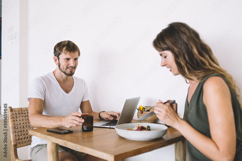 Caucasian couple in love discussing fresh ingredients of vegetable salad during lunch time in cafe interior with good internet connection for distance job via laptop device, concept of friendship Caucasian couple in love discussing fresh ingredients of vegetable salad during lunch time in cafe interior with good internet connection for distance job via laptop device, concept of friendship