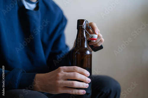 the man holding the glass bottle of alcohol sitting at home in depression, bad habit problem