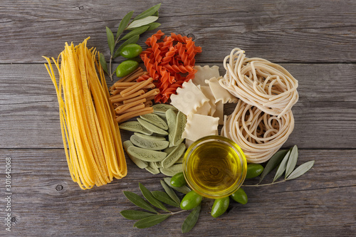 Different kinds of of pasta on the wooden background. Spaghetti. Olive oil. photo