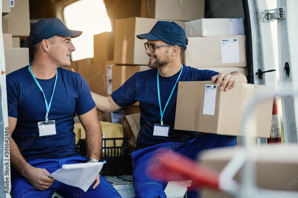 Two happy couriers talking while preparing packages for a delivery. Two happy couriers talking while preparing packages for a delivery.