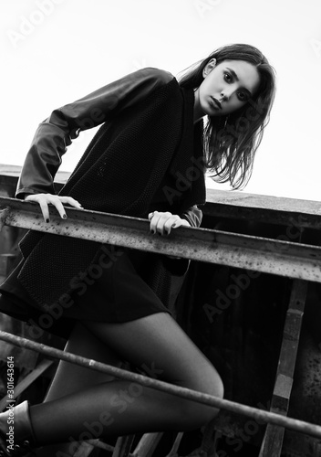 Fashion shot: portrait of beautiful rock girl (informal model) dressed in black jacket and skirt. Black and white