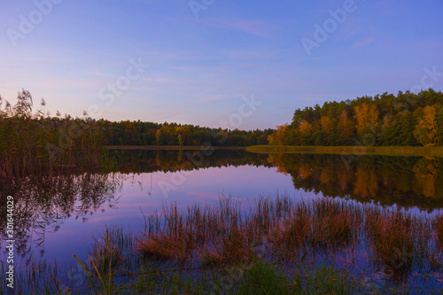 Autumn landscape sunset lake violet sky clouds trees on the shore reflection in the water