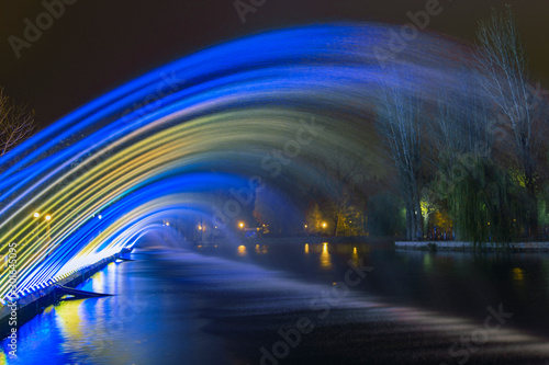 long exposure fountain streams highlighted by blue and yellow spotlight urban attraction point at night time 