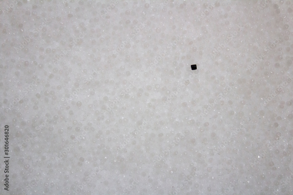 black granule lying on the surface of white plastic granules. black granule lying on the surface of white plastic granules.