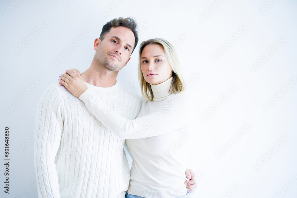 Young beautiful couple wearing casual t-shirt standing over isolated white background with serious expression on face. Simple and natural looking at the camera. Young beautiful couple wearing casual t-shirt standing over isolated white background with serious expression on face. Simple and natural looking at the camera.