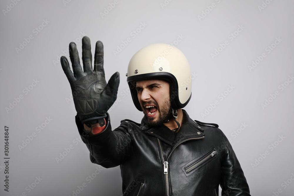 Close-up portrait of biker with white helmet making stop signs with his hand. Isolated. Close-up portrait of biker with white helmet making stop signs with his hand. Isolated.