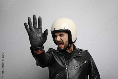 Close-up portrait of biker with white helmet making stop signs with his hand. Isolated.