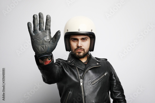 Close-up portrait of biker guy with white helmet making stop signs with his hand. Isolated.
