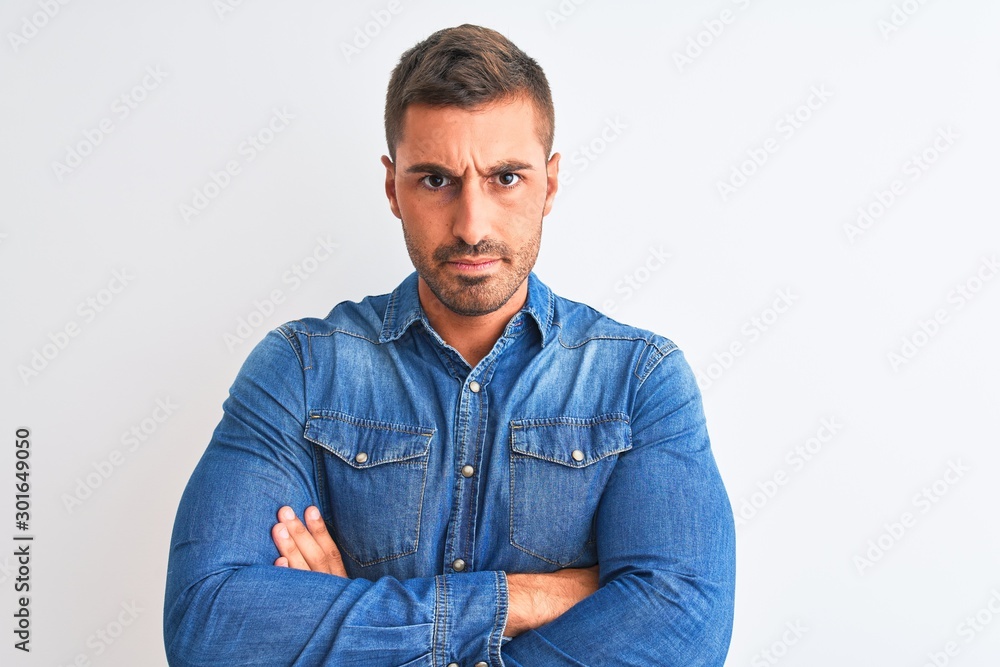 Young handsome man wearing denim jacket standing over isolated background skeptic and nervous, disapproving expression on face with crossed arms. Negative person. Young handsome man wearing denim jacket standing over isolated background skeptic and nervous, disapproving expression on face with crossed arms. Negative person.