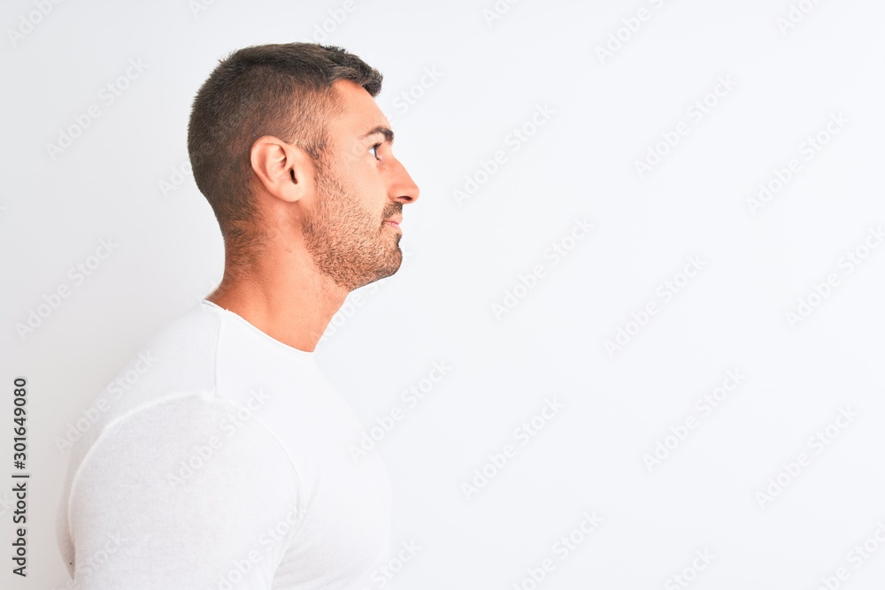 Young handsome man wearing white shirt over isolated background looking to side, relax profile pose with natural face with confident smile.