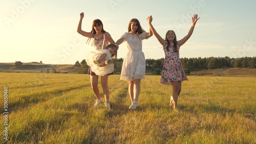 mother and little daughter with sisters walking in park. Happy young family with a child walking on summer field. Children and mom are playing in the meadow. concept of a happy family.